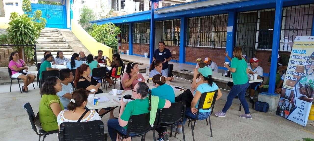 Taller comunitario al aire libre con participantes en mesas de trabajo